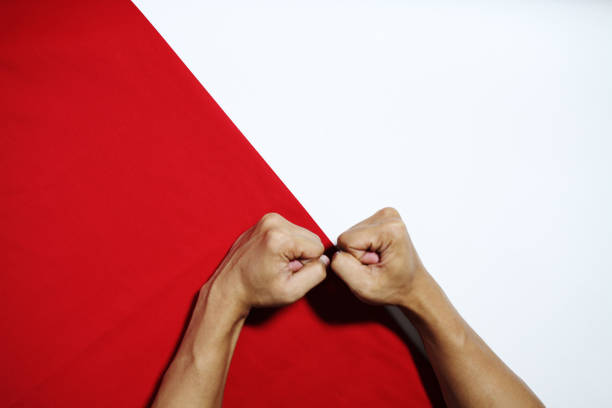 Man breaking through red paper with fist, closeup