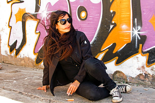 istock Smoking woman in black at the graffiti brick wall 175360520