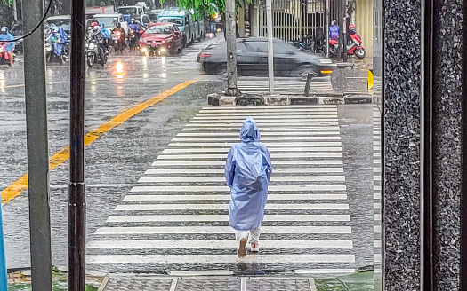 A woman is crossing a zebra crossing on a rainy day