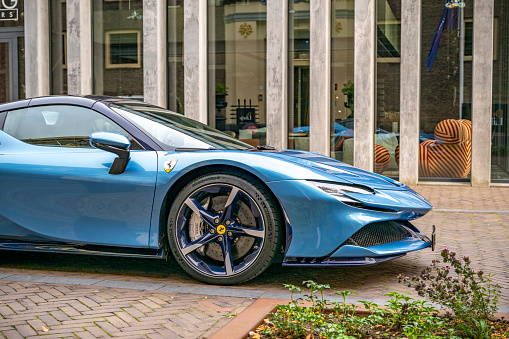 Ferrari SF90 sports car in light blue parked on the street in Zwolle. The Ferrari SF90 Stradale, unveiled in 2019, is a hybrid sports car and the first series-production Plug-In Hybrid Electric Vehicle (PHEV) from Ferrari. The SF90 Stradale is powered by a 4.0-liter twin-turbocharged V8 engine coupled with three electric motors – two at the front and one at the rear.