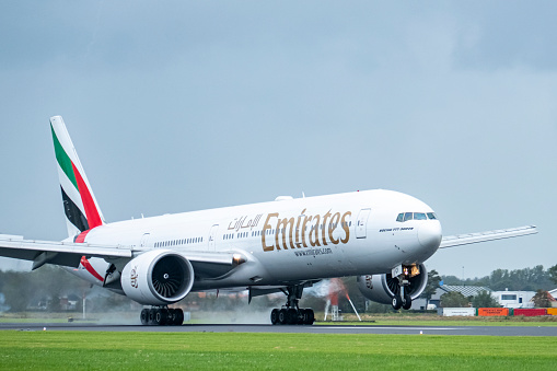Emirates Airline Boeing 777-300ER landing at Schiphol airport on the Polderbaan during an overcast day at Amsterdam Schiphol airport in The Netherlands.
