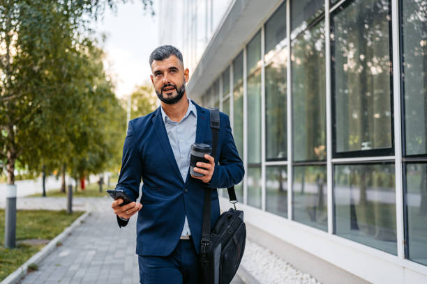 istock Businessman Using Phone And Drinking Coffee In Front Of Corporate Building 1753674076