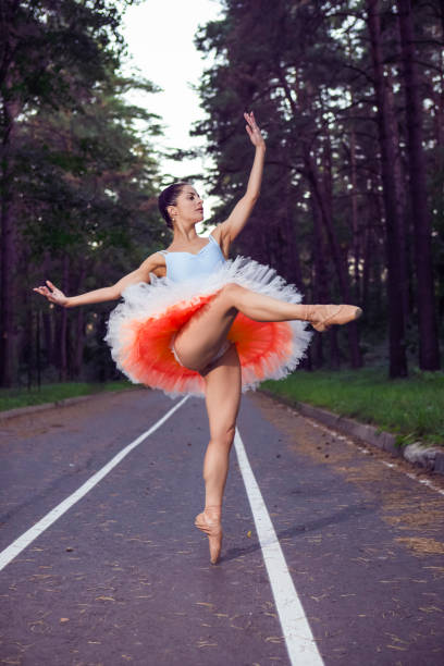 istock Sexy Slim Young Caucasian Ballet Dancer in Light Orange Blue Tutu Posing in Dance Pose During Ballet Pas in Summer Forest With Lifted Hands 1753689850