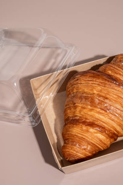 istock Delicious croissant in a lunch box closeup on a beige background with hard light 1753701174