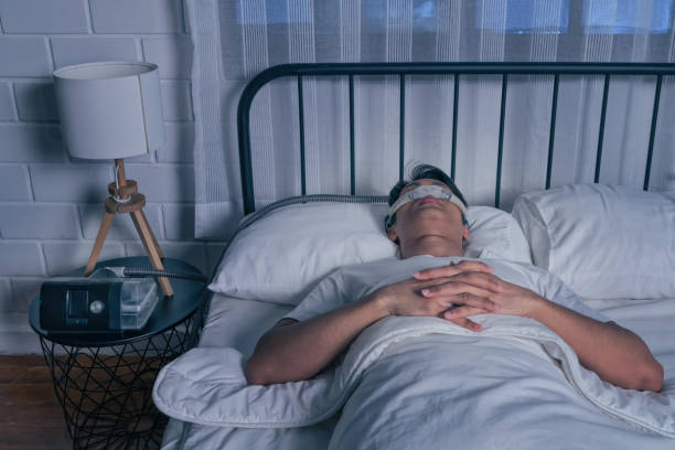 Asian man wearing Cpap mask sleeping smoothly in bed all night without snoring stock photo