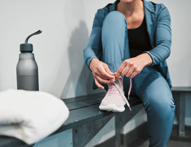 Fitness, tie shoes and sport woman in gym locker room for exercise, workout, healthy lifestyle and wellness. Person and shoelaces in sportswear for training, cardio and strong muscle for competition fitness, zapatos de corbata y mujer deportiva en el vestuario del gimnasio para ejercicio, entrenamiento, estilo de vida saludable y bienestar. persona y cordones en ropa deportiva para entrenamiento, cardio y músculo fuerte para competición