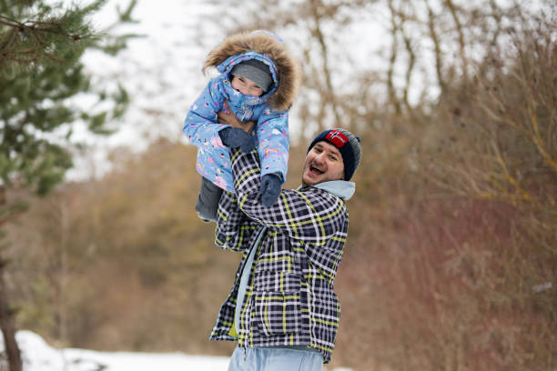 Daughter on a piggy back ride with her dad in winter forest.