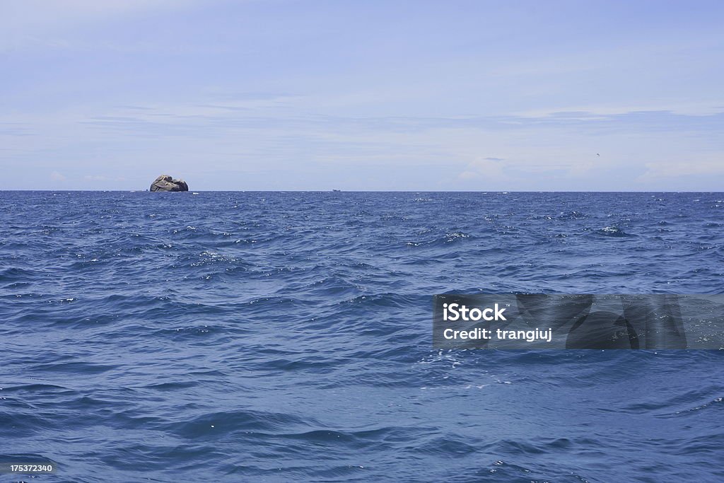 solo rock on blue the sea A solo rock islet on the blue sea, off Cam Ranh bay, Nha Trang, Vietnam Blue Stock Photo
