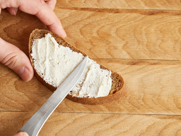 istock Spread sour milk cheese on a slice of bread with a knife. 1753723709