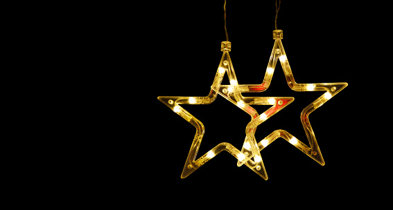 Dark black colored 3D or three dimensional horizontal blank Xmas or Diwali celebrations festive background, poster or wallpaper. Can be used as Christmas party wallpaper, backdrop, celebration, festive background, gift wrapping sheet. There are two stars lights hanging from the top of a wall leaving plenty of copy space.