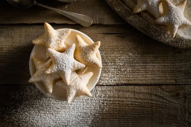Sugar dusted puff pastry stars on dark wooden board top view