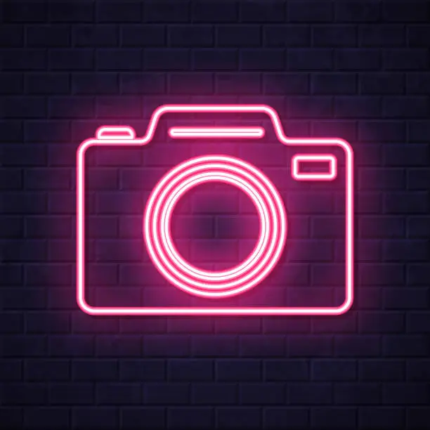 Vector illustration of Photo camera. Glowing neon icon on brick wall background