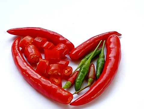 Fresh chili placed in heart shaped on a white background. Eating fresh chili has a positive effect on heart desires risk factors. Close -up shot of the fresh chili.
