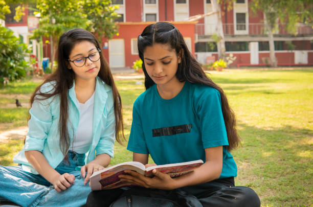 istock Female Students discussing together on a book in university campus ground. 1753762061