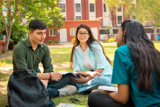 istock Students discussing together on a book in university campus ground. 1753764753