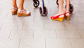 Young couple wearing high heel sandals with baby stroller along the sidewalk.