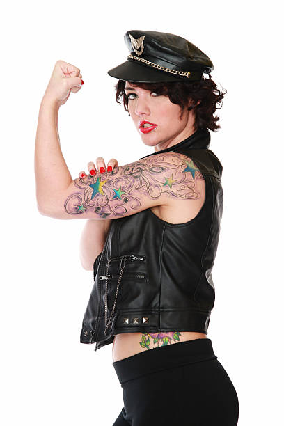 Retro Pinup in biker clothes witrh tattooes Cute caucasian female with black hair, black 50's biker cap, bra, spandex pants, jacket Isolated on white. black pin up girl tattoos stock pictures, royalty-free photos & images