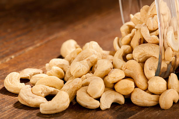 Cashews Spilled cashews from a glass dish bowl cashew photos stock pictures, royalty-free photos & images
