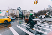 Delivery man riding bicycle by Union square on rainy winter day in New York City , US