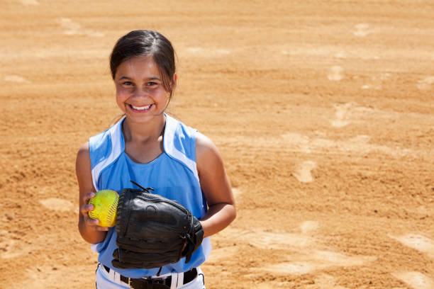 Softball player "Hispanic girl (10 years) playing softball, standing on pitcher's mound." softball pitcher stock pictures, royalty-free photos & images