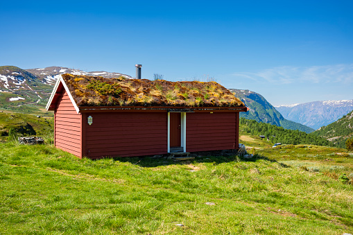 Ekrehytta mountain range seen from Turtagro, Norway at Jotunheimen National Park, with clear skies during a summer day.  A red cabin overlooks the valley.