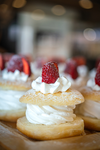 Pieces of strawberry cake with whipped cream in the middle, there are preparing in shelf at the bakery shop. Sweet food object, close-up and selective focus.