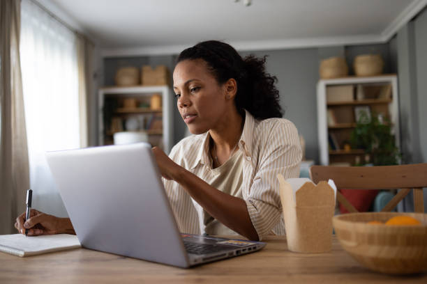 istock Black female freelancer taking notes while working on laptop at home. 1753818337