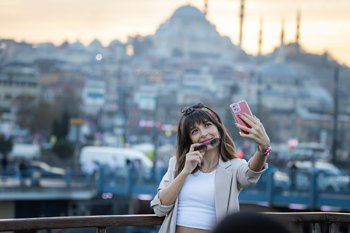 Pretty young lady is taking a selfie with Istanbul cityscape background.
