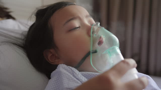 Mother taking care of her daughter using an inhaler, nebulizer treatment. Asthma treatment
