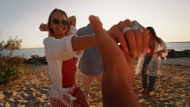 POV: Beautiful Blonde Girl Leading her Boyfriend to Dance with Friends on a Beach. Stylish Men and Women Having Fun, Enjoying Their Youth and Summer Warm Days. Travelling Content and Footage