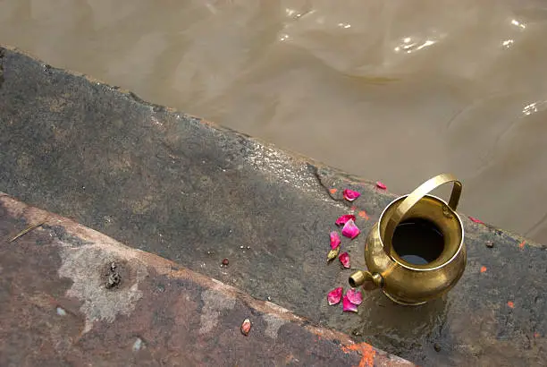 Copper kettle at the edge of the river Ganges.It is used for pouring the holy water of the river as part of the offering to Mother Ganga.