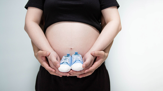 Pregnant lady holding baby shoe