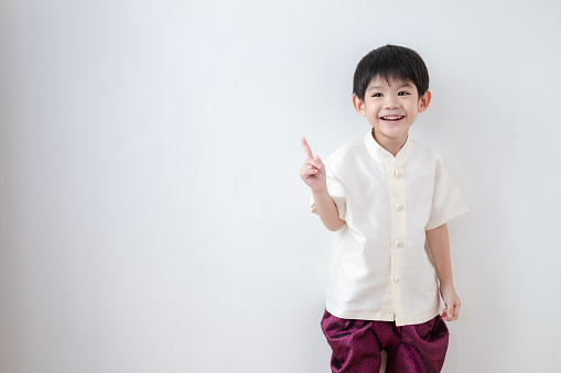 Asian boy Wearing traditional Thai clothing, standing with index finger upwards. on a white background
