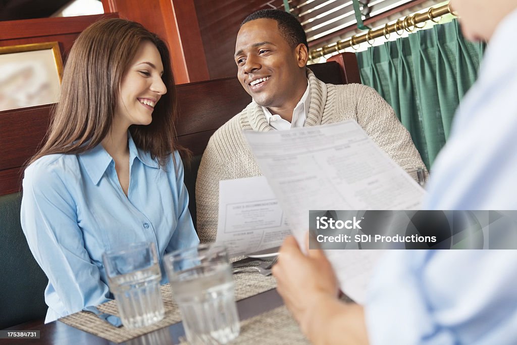 Amigos leer el menú en un restaurante booth - Foto de stock de Saludar libre de derechos