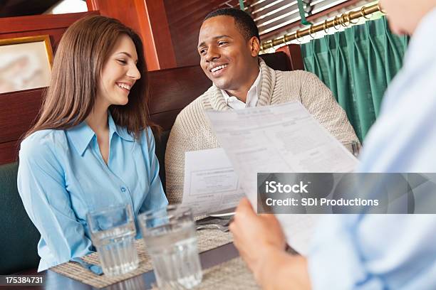 Amigos Leer El Menú En Un Restaurante Booth Foto de stock y más banco de imágenes de Saludar - Saludar, Agua, Cliente