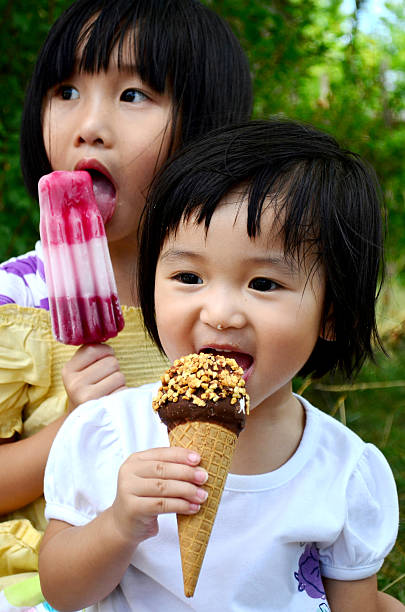 Eating ice cream Little girls eating ice-cream and popsicle asian little chinese girls eating ice cream stock pictures, royalty-free photos & images