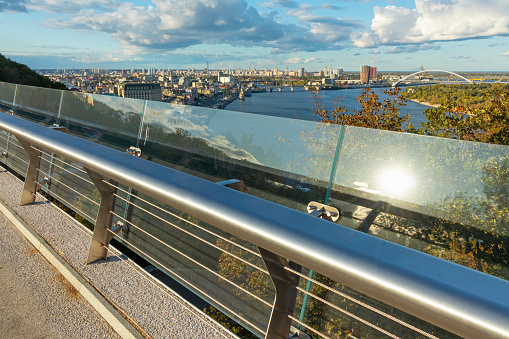 A barrier made of metal and glass on a pedestrian bridge with an observation deck and a view of the city. Tourist place