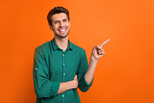 Photo of young man brunet wear orange stylish shirt direct finger mockup presentation check list to do isolated on orange color background.