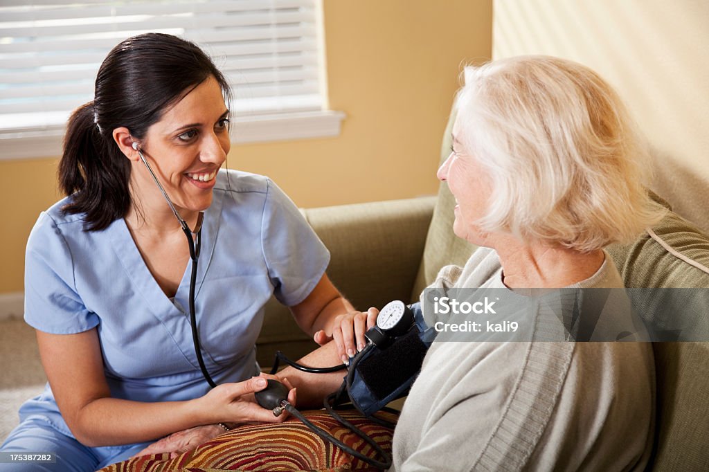 Enfermera senior mujer tomando la presión arterial - Foto de stock de Enfermera libre de derechos