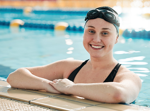 Fitness, swimming pool and portrait of a sports woman with a smile for workout, competition or exercise. Happy athlete person or professional swimmer at training for performance and challenge