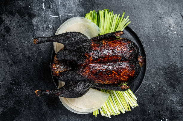 traditional whole roasted christmas peking duck with herbs and sauce. black background. top view - fine dining grilled spring onion healthy lifestyle imagens e fotografias de stock