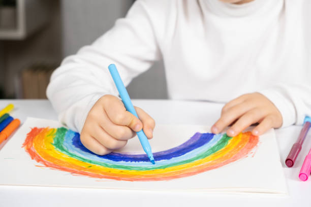 istock A small child draws a rainbow with felt-tip pens in a sketchbook while sitting at a table 1753873497