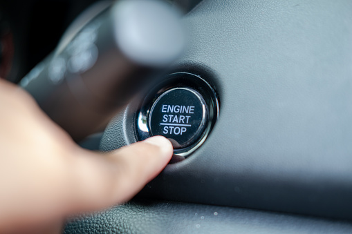 Male finger pressing engine start stop button