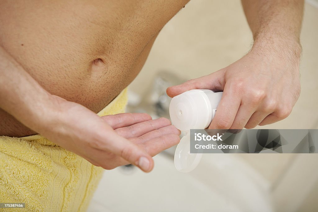 Using comsetics man using cosmetic in his bathroom in the morning Adult Stock Photo