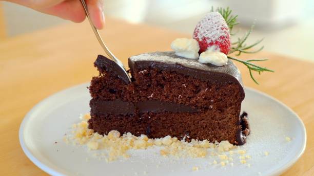 istock Man hand taking a bite of moist, delicious chocolate cake with a spoon 1753874795