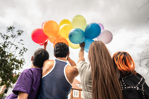 Rear view of lgbtqia+ people holding balloons outdoors
