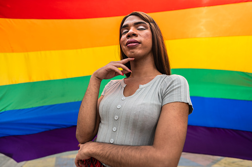 Portrait of a lgbtqia+ woman with rainbow flag on background