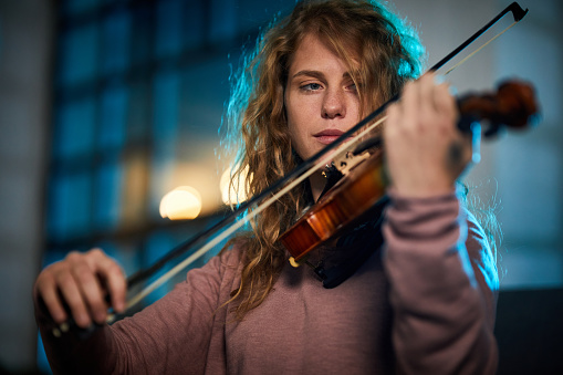 Young woman enjoying while playing her violin.