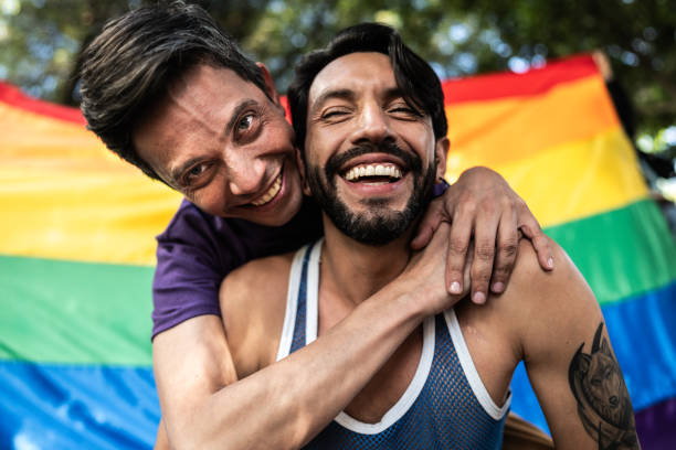 istock Gay couple piggyback outdoors with rainbow flag on background 1753876331