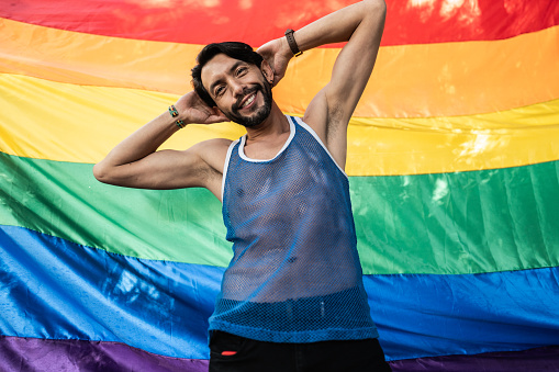 Portrait of a mature gay man with rainbow flag on background